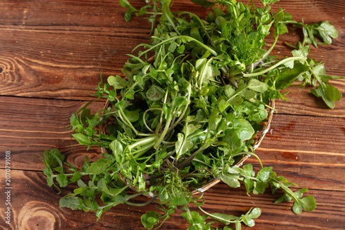 Fresh leafy greens in a basket on rustic wooden table
