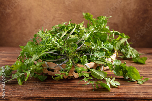 Fresh Wild Greens in a Basket on Rustic Wooden Table