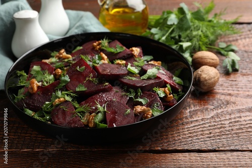 Obraz na płótnie Delicious salad with beetroot, walnuts, dill and parsley on wooden table, closeu