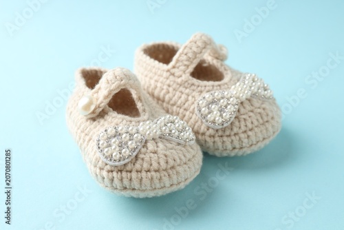 Obraz na płótnie Cute knitted baby shoes on light blue background, closeup