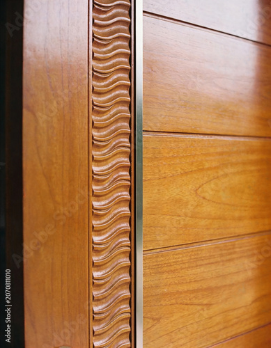Close-up of a wooden door with decorative carved panel and metal trim
