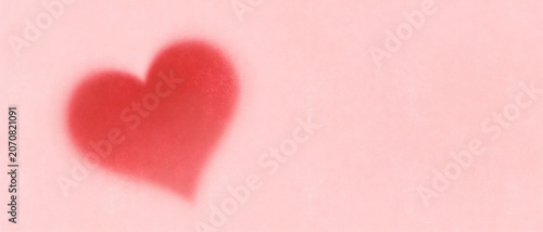 Soft red heart shape on a pale pink textured background with copy space