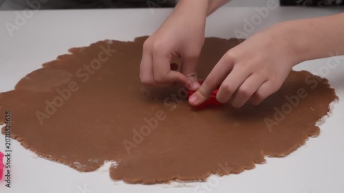 Mother and child hands press cutters into gingerbread dough on table. Family prepares cookie shapes for holiday baking recipe pastry culinary lifestyle lesson using raw sweet brown chocolate.