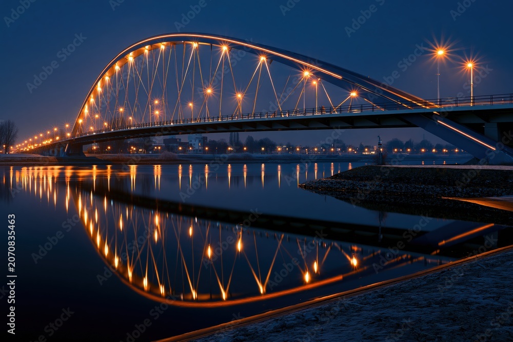 Fototapeta premium Bridge illuminated at night over river reflection long exposu