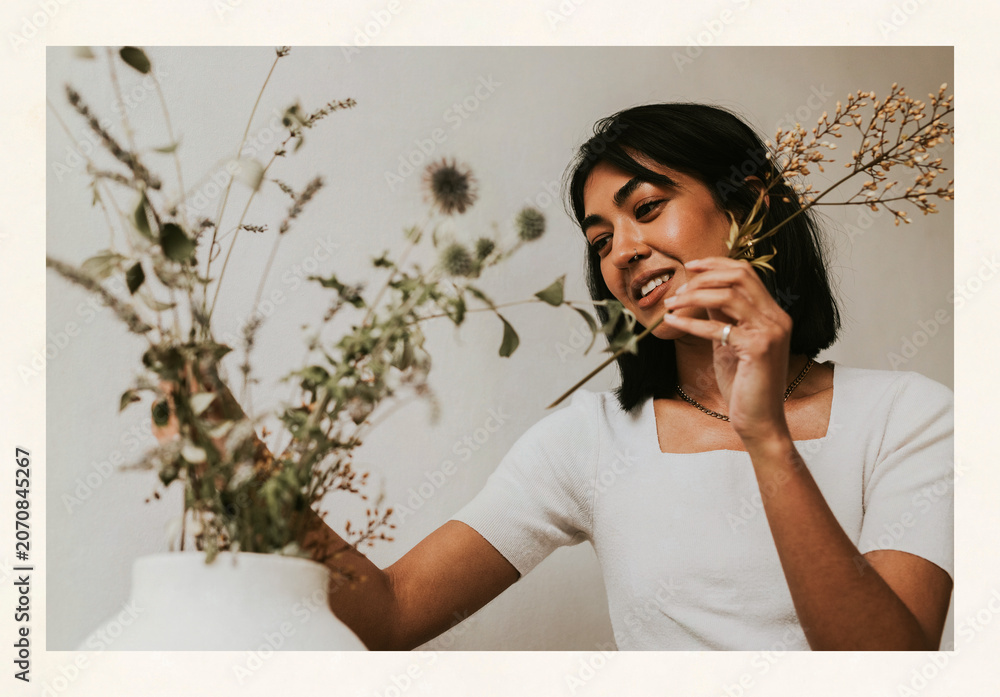 Fototapeta premium Woman arranging dried flowers in white vase indoors