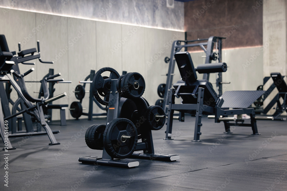Fototapeta premium Weight plate rack and exercise machines in modern gym