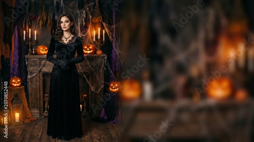 Woman in Dark Dress Stands Near Carved Pumpkins and Candles in a Decorated Ro...
