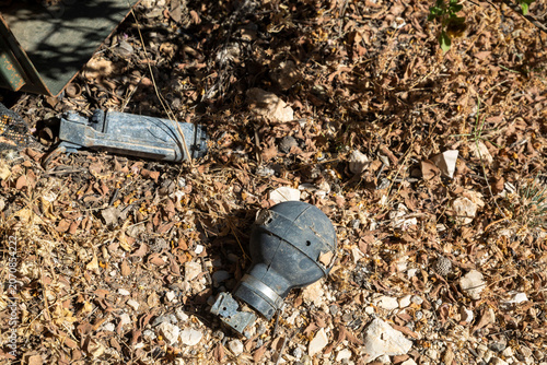 Fotografie Old plastic grenade casing or military equipment lying discarded on dry leaves