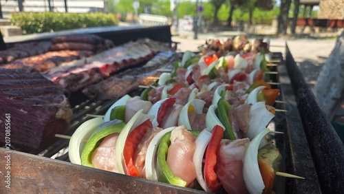 Fotografie Grilled sausages and assorted meat sizzling on an outdoor barbecue grill for sum