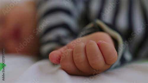 Obraz na plátně Tiny toddler hand gently curled while sleeping on bed, intimate childhood detail
