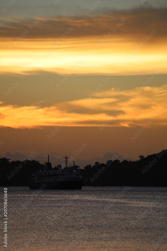 Obraz premium Golden Sunset Seascape with Ship Silhouette and Ocean Reflection