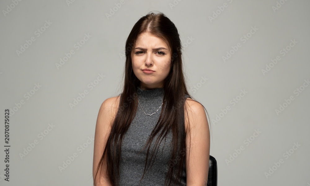 Naklejka premium Young woman showing an expression of skepticism, doubt, and grimacing at something unappealing or disappointing
