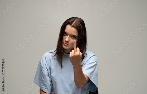 Tablou pe pânză Young woman showing middle finger gesture expressing anger, defiance, and rebell
