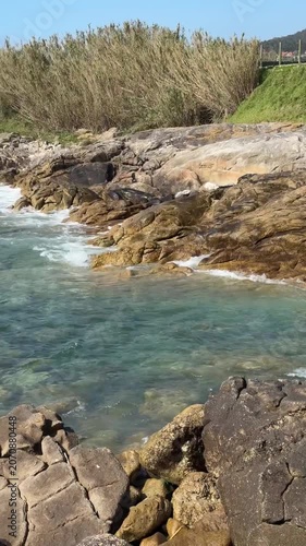 Rocky Atlantic shoreline, clear coastal water, natural stone formations, Portuguese Camino de Santiago, rugged seaside landscape, dynamic ocean movement. Hiking destination, nature exploration