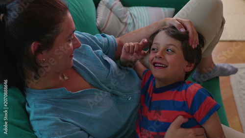 Bilde på lerret Mother and son lying together on sofa sharing playful affectionate moment warm c