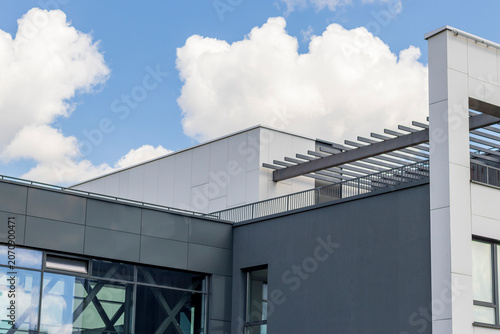 Modern commercial building facade with grey panels, glass windows, and blue sky reflection, Urban