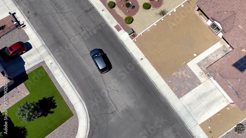 Aerial view of a silver SUV driving through a southwestern suburban neighborhood and pulling into a driveway