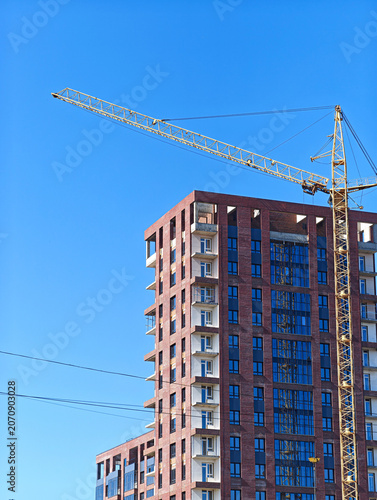 The process of constructing a monolithic-brick residential building using a tower crane.