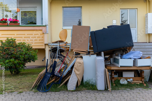 Piles of discarded furniture and items near a building in a residential area during the day