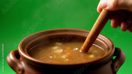 Steaming Hot Vegetable Soup Being Scooped from Rustic Brown Clay Pot