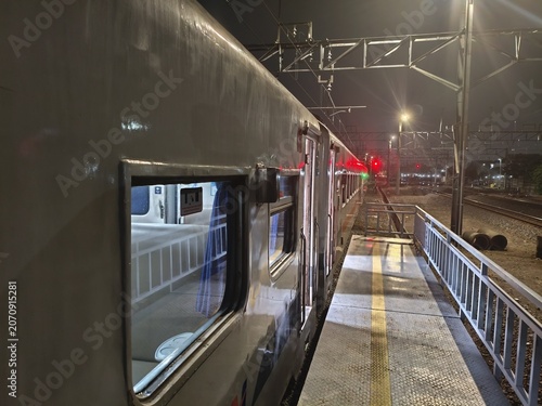 Night Train Station Platform: Close-up of Train Car Window and Tracks at Twilight
