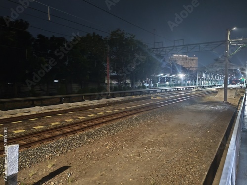 Night train station with Mercure Hotel sign and railway tracks illuminated by artificial lights