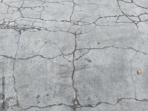 Cracked Concrete Texture Background with Natural Light and Dry Leaves