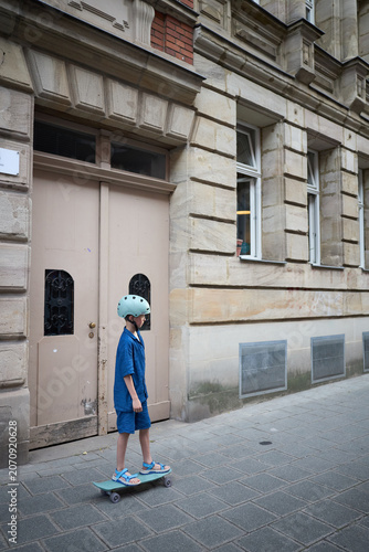 Young child skateboarding in urban setting wearing safety gear and stylish outfit