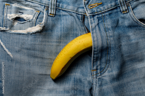 Fotografija Creative minimalist shot of a yellow banana peeking out from opened denim jeans fly