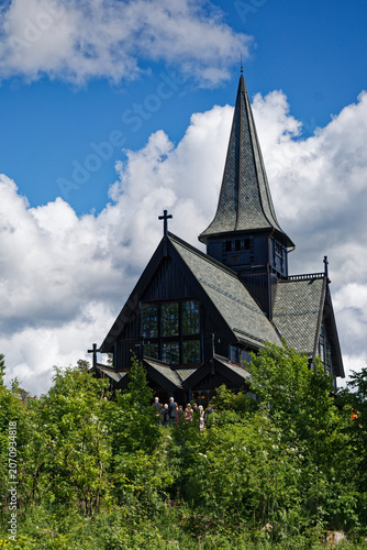 Dramatic Dark Wooden Church, Spire Reaching Skyward, with Attendees and Greenery