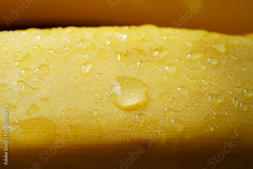Fresh Banana with Water Droplets – Tropical Fruit Macro Background. Macro close-up of a ripe yellow banana covered with sparkling water droplets.