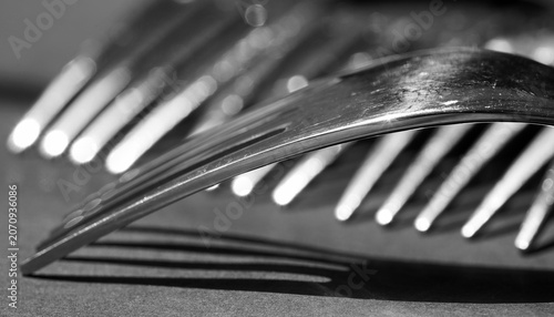 Artistic black and white close-up of stainless steel forks arranged in a layered composition.