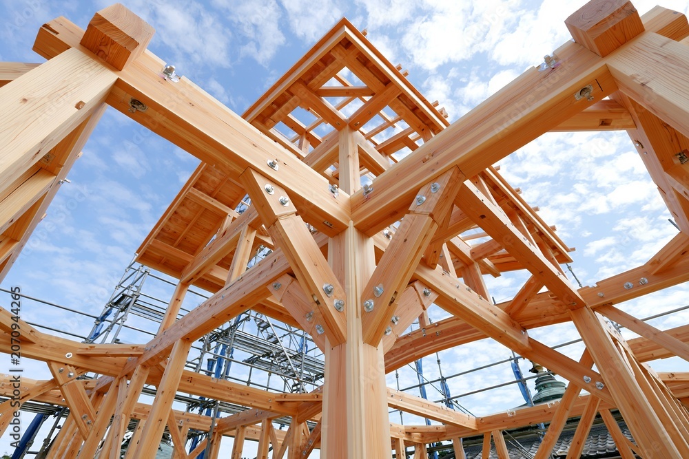 Obraz premium 青空広がる新築現場で組まれた木造建築の強固な構造