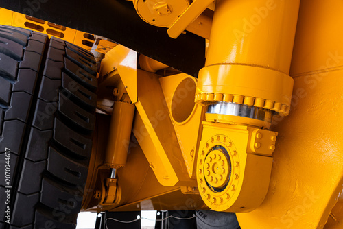 Fotografie Tight close-up showing the yellow painted suspension components and large tire of heavy construction machinery