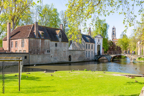 Begijnhof bridge leading to Beguinage at Lake of Love and St. Salvator's cathedral tower in Brugge, Belgium