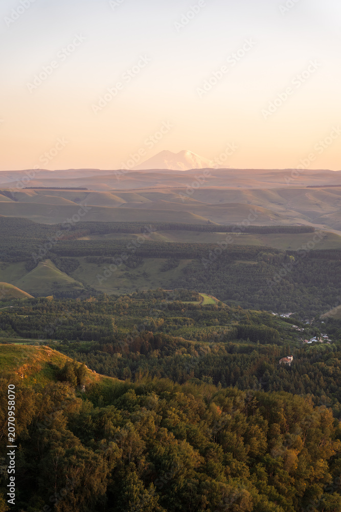 Naklejka premium Layers of green mountains and hills in the haze during sunset. Panoramic View of Green hills and Meadow.
