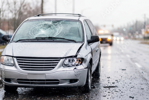 Damaged silver minivan with cracked windshield after accident