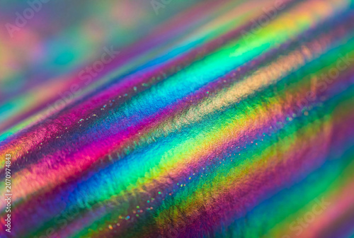 Detailed close up of a shimmering holographic surface with diagonal rainbow colors