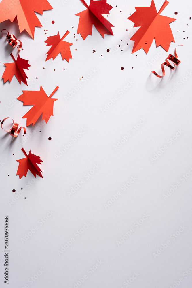 Obraz premium Red paper maple leaves and curled ribbon for Canada Independence Day celebration on white vertical background