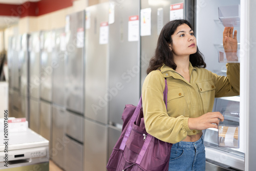 Fotografia Latin woman chooses a large and roomy refrigerator for her new apartment