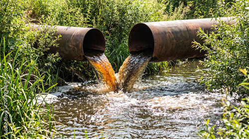 Canvas-taulu Industrial sewage outflow from large metal pipes into a river surrounded by lush