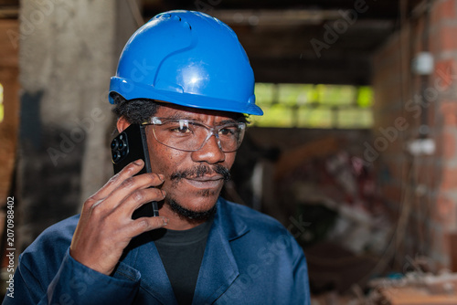 Worker talks on phone while wearing safety gear in a construction area