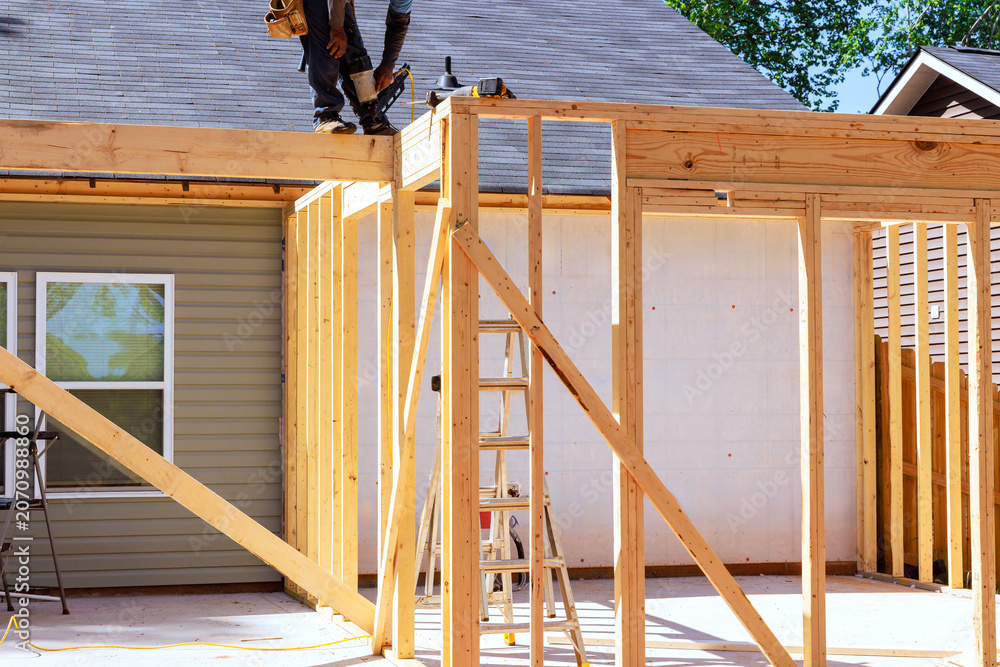 Obraz premium Workers are assembling wooden frame next to house with ladder during trusses frame