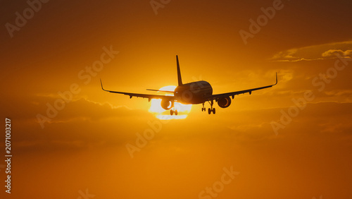 Photos Airplane silhouetted against a vibrant sunset with clouds