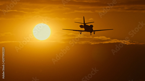 Silhouette of a small airplane flying against a vibrant sunset sky