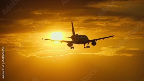 Airplane flying against a dramatic sunset with golden clouds and sun
