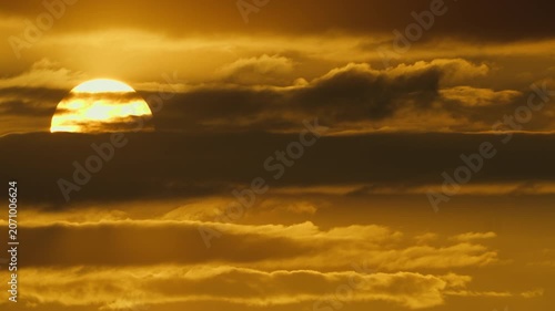 Dramatic sunset with sun partially obscured by dramatic clouds