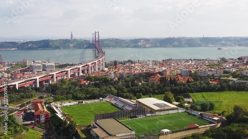 Aerial drone shot of Lisbon cityscape with Ponte 25 de Abril above Tagus River in Portugal. Urban landscape with football field, residential district and waterfront skyline