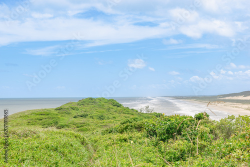 Bild auf Leinwand Exuberantes colinas verdes costeras y paisaje de playa de arena bajo un cielo az