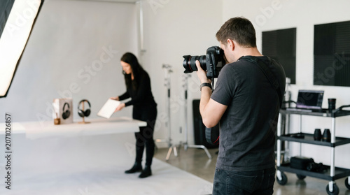 Professional photographer and female assistant capturing product images with assistant in studio